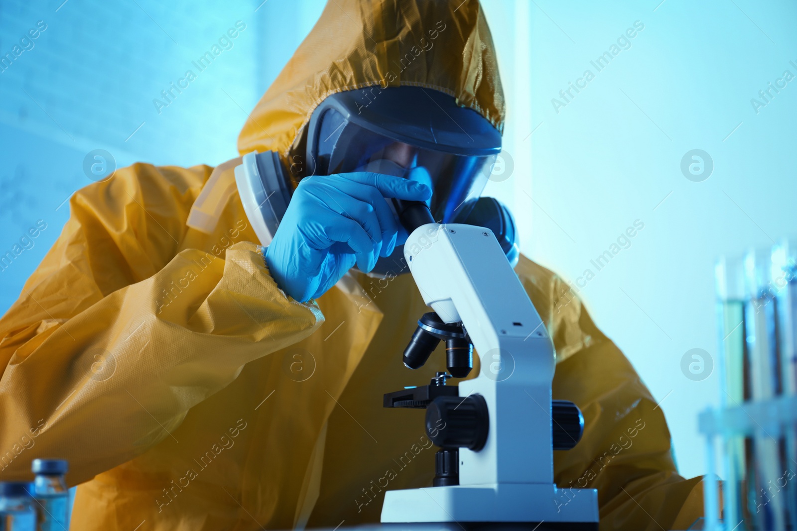 Photo of Scientist in chemical protective suit using microscope at laboratory. Virus research