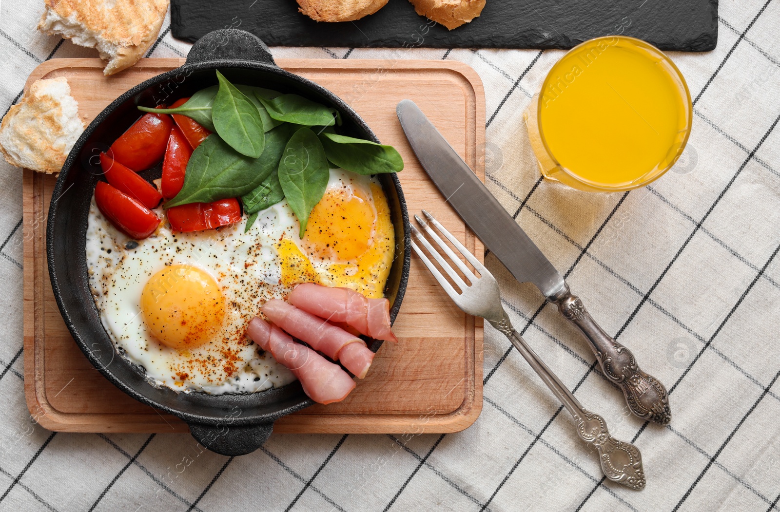 Photo of Delicious fried eggs with spinach, tomatoes and ham served on table, flat lay