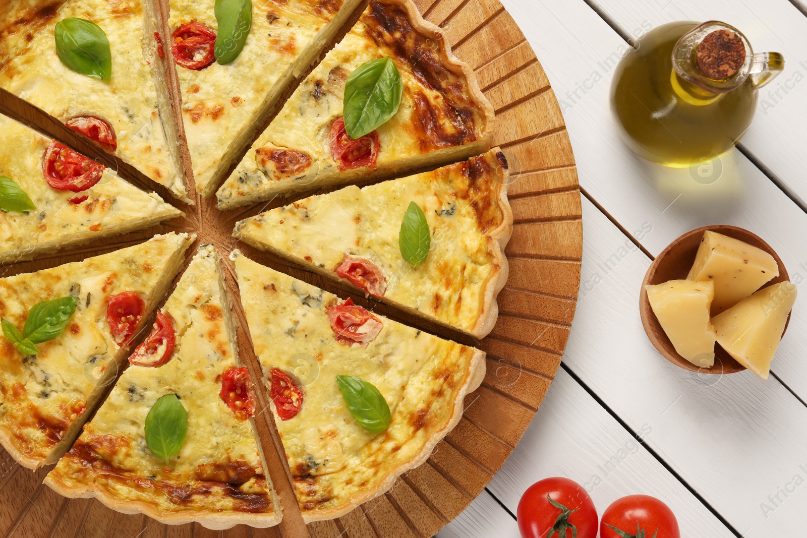 Photo of Delicious homemade cheese quiche and ingredients on white wooden table, flat lay