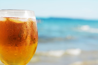 Photo of Cold beer in glass on beach, closeup. Space for text