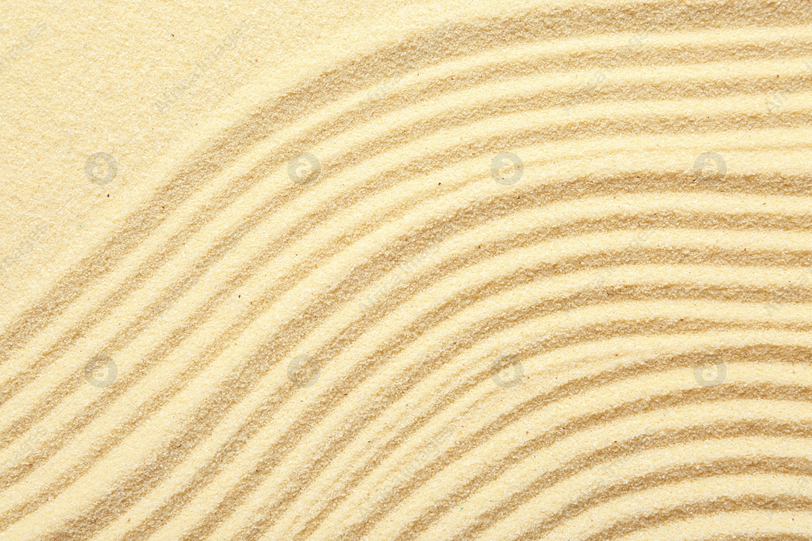 Photo of Zen rock garden. Wave pattern on beige sand, top view