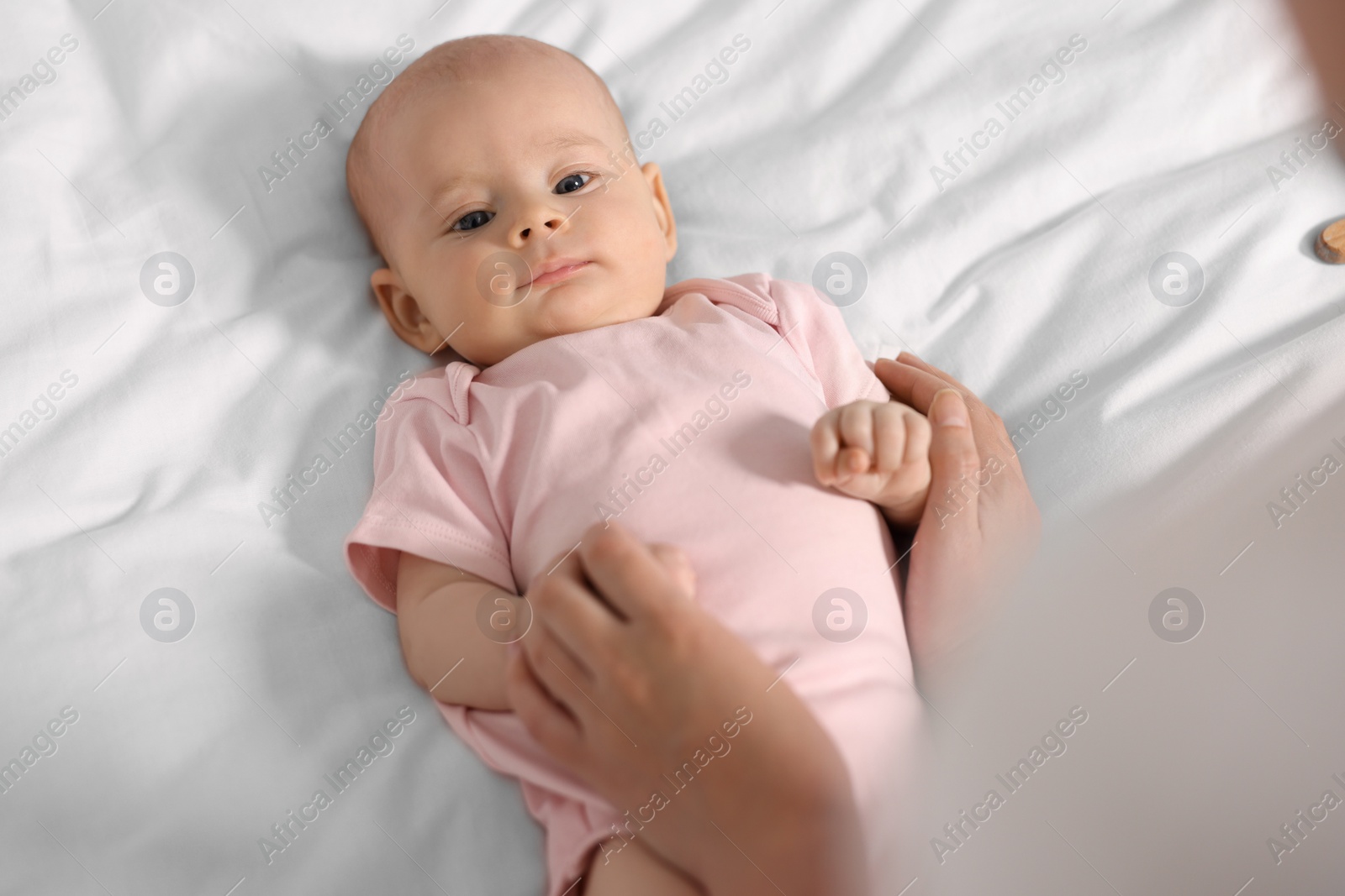 Photo of Mother with her cute little baby on white sheets