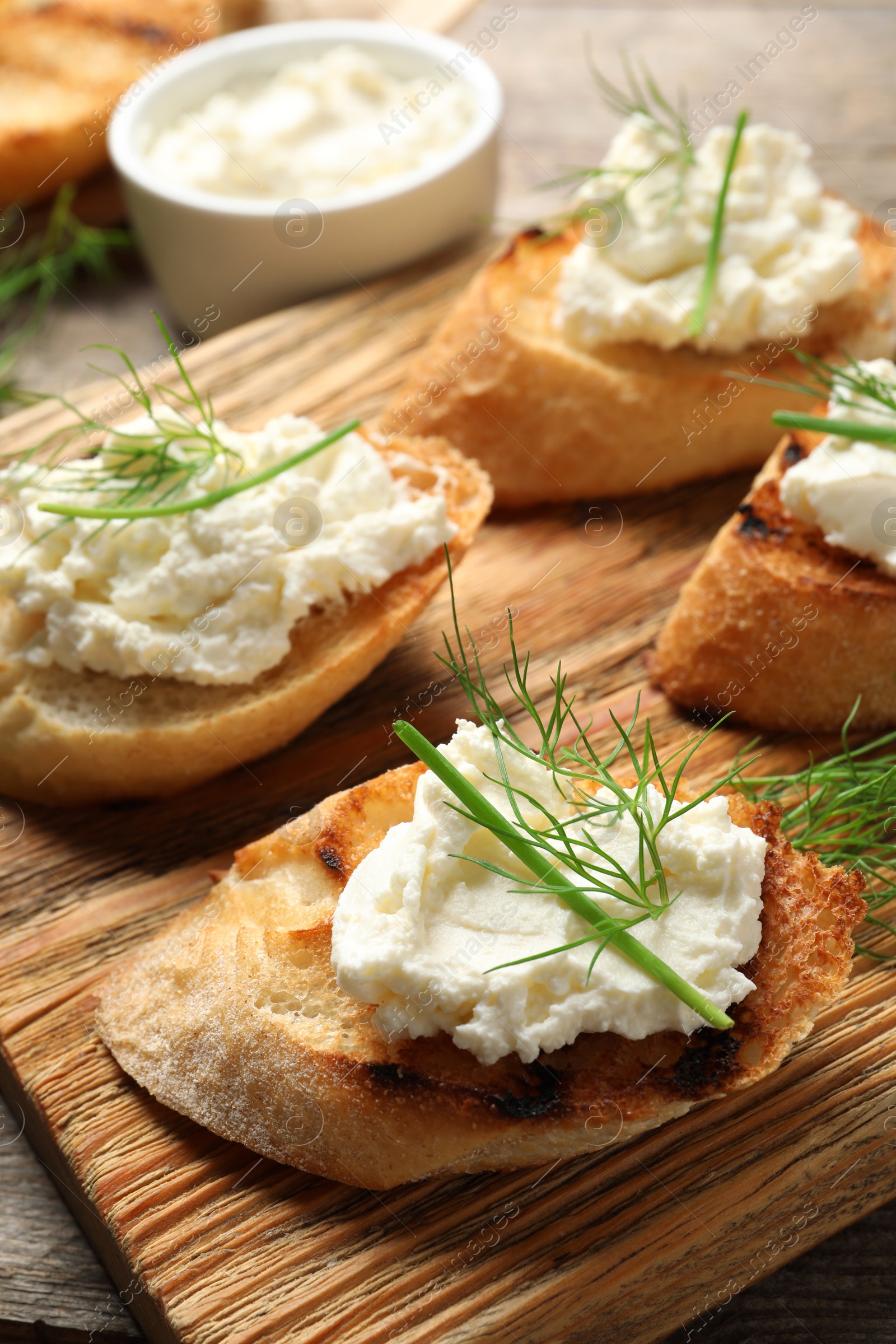 Photo of Toasted bread with tasty cream cheese on wooden board