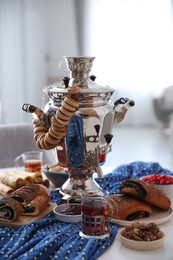 Traditional Russian samovar with treats on white table at home