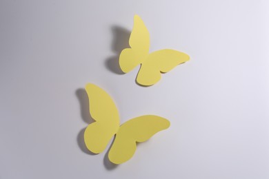 Photo of Yellow paper butterflies on light background, top view