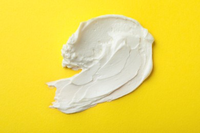 Photo of Smear of delicious cream cheese on yellow background, top view