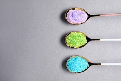 Photo of Spoons with colorful sea salt on light grey table, flat lay. Space for text