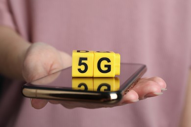5G technology, Internet concept. Woman holding smartphone with yellow cubes, closeup