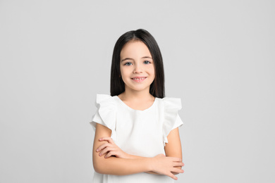 Portrait of cute little girl on light grey background