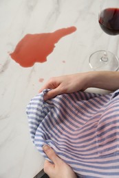 Photo of Woman with wine stain on her shirt and spilled wine at white marble table indoors, above view