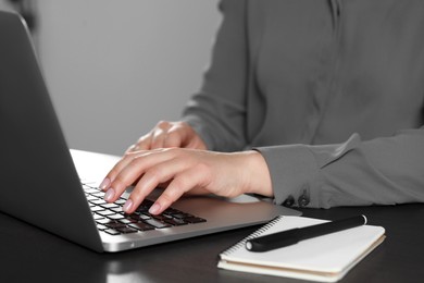 Woman typing on laptop at table, closeup. Electronic document management