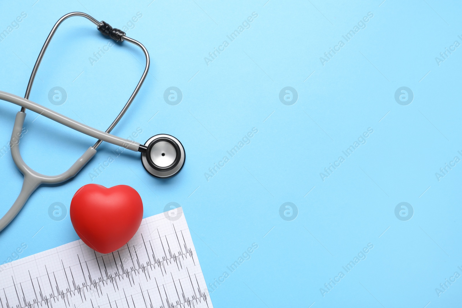 Photo of Stethoscope, cardiogram and red decorative heart on light blue background, flat lay with space for text. Cardiology concept