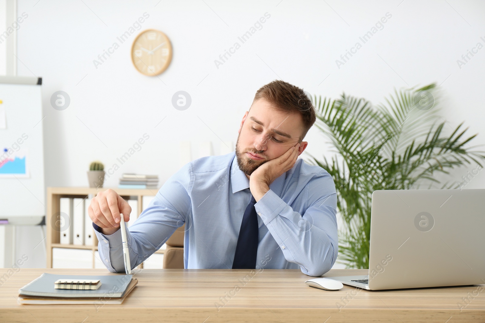 Photo of Lazy young office employee procrastinating at workplace