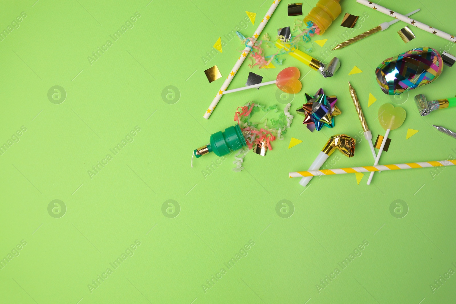 Photo of Party poppers with colorful streamers, blowers and festive decor on light green background, flat lay. Space for text