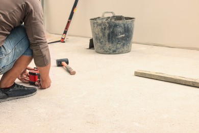 Photo of Worker and different tools on floor indoors. Tiles installation process