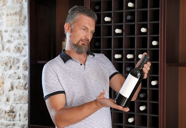 Photo of Man with bottle of expensive wine indoors