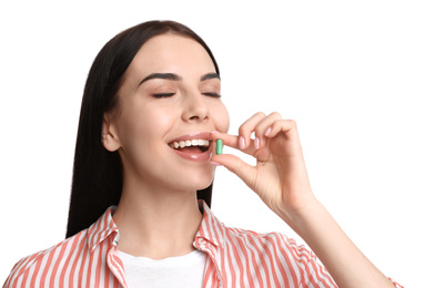 Photo of Young woman taking vitamin capsule on white background
