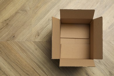 Photo of Empty open cardboard box on floor, top view. Space for text