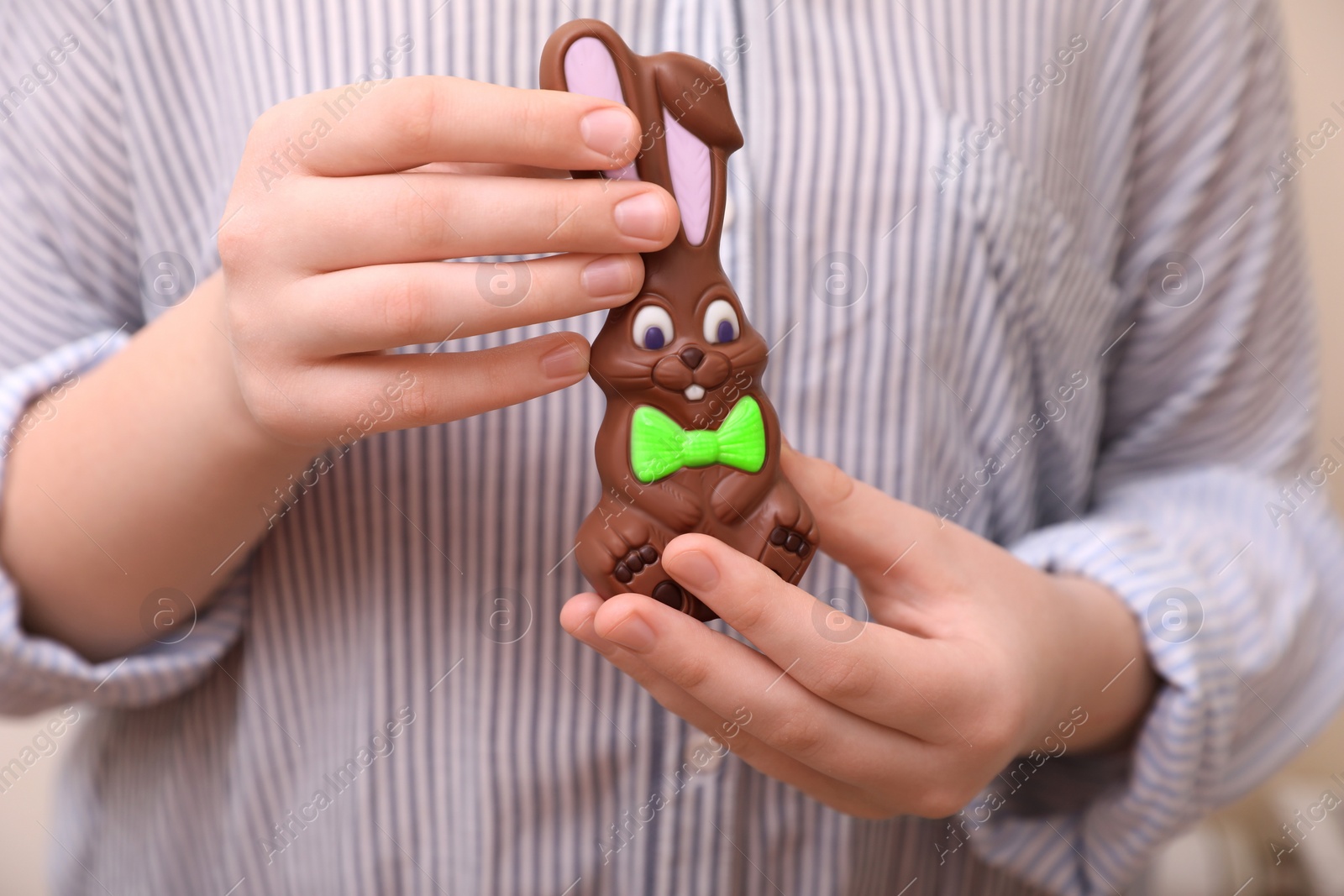 Photo of Woman with chocolate Easter bunny on beige background, closeup