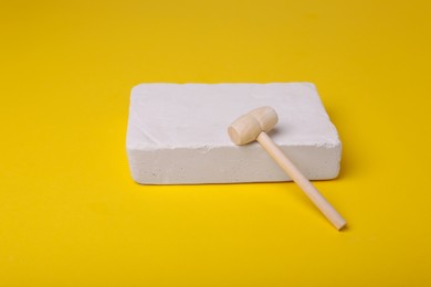 Photo of Educational toy for motor skills development. Excavation kit (plaster and wooden mallet) on yellow background
