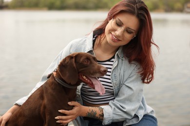 Photo of Woman with her cute German Shorthaired Pointer dog outdoors