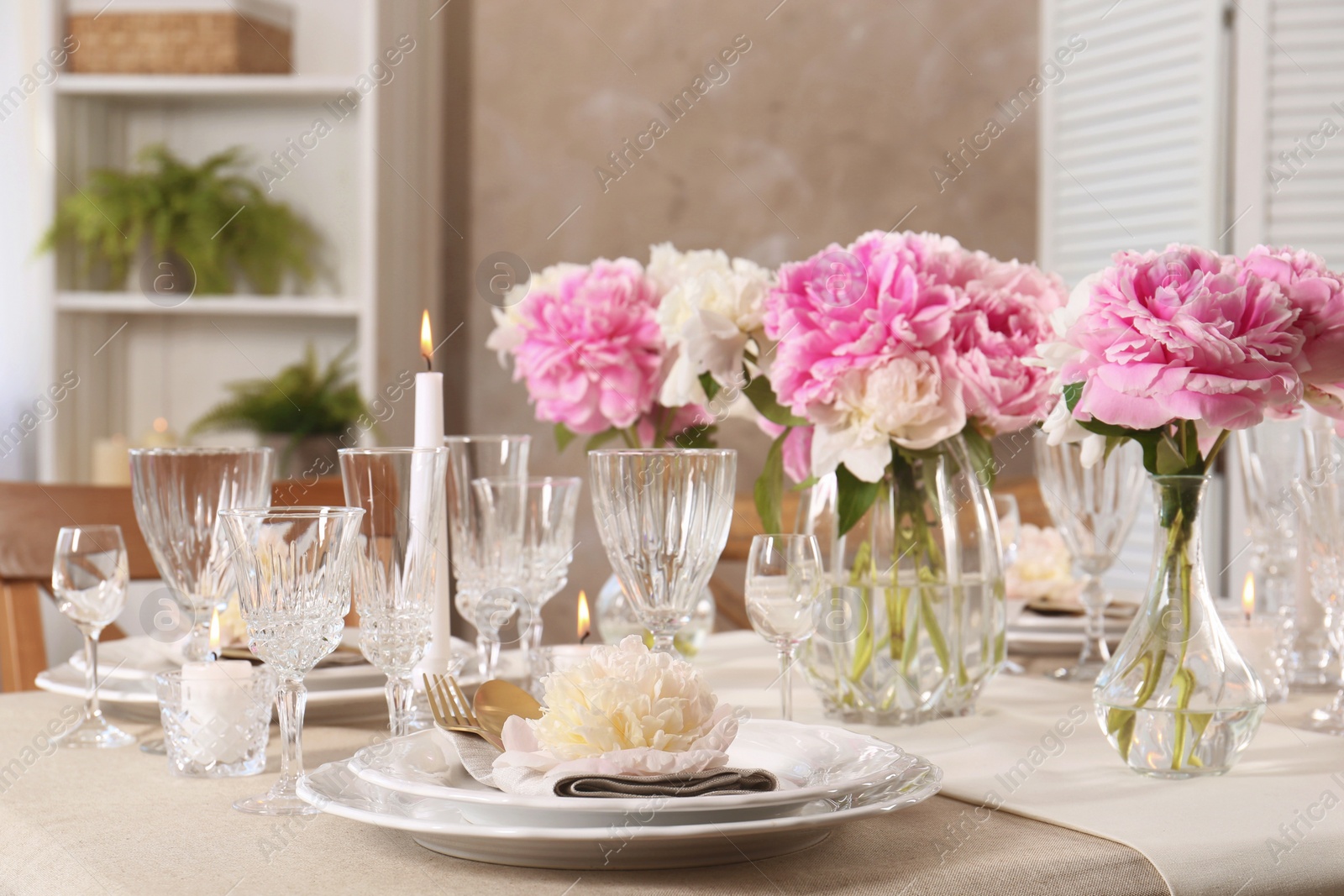 Photo of Stylish table setting with beautiful peonies and burning candles indoors