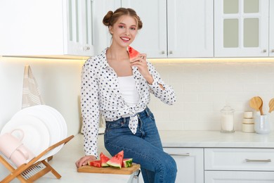 Beautiful teenage girl with slices of watermelon near countertop in kitchen