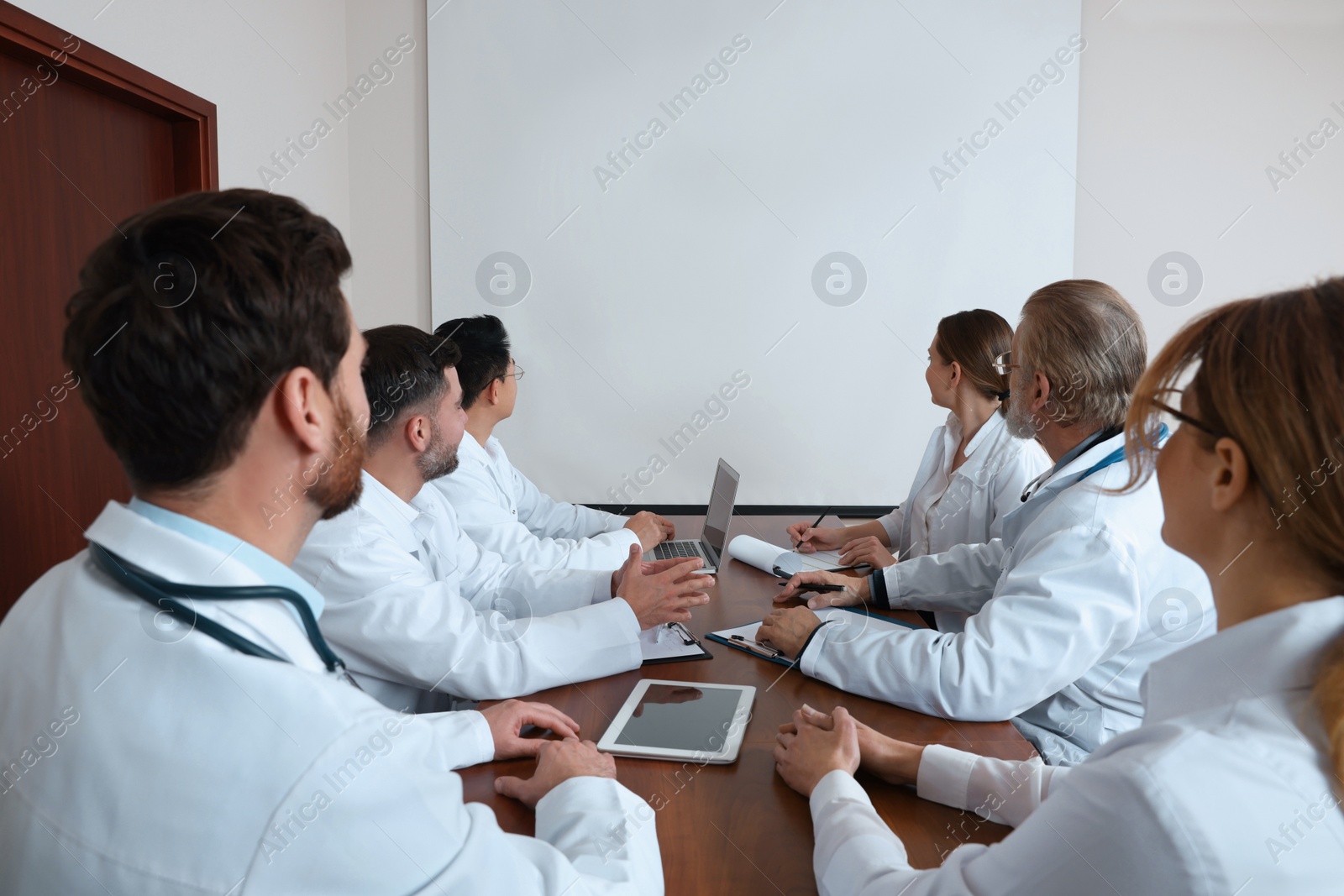 Photo of Team of doctors using video projector during conference indoors