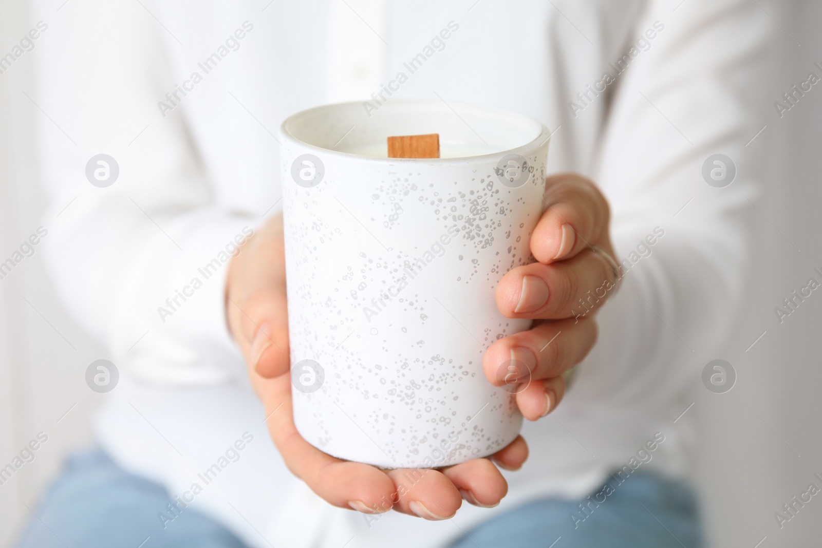 Photo of Woman holding candle with wooden wick on grey background, closeup