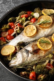 Photo of Baked fish with vegetables, rosemary and lemon on black textured table, above view