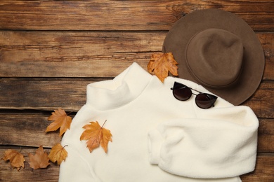 Photo of Flat lay composition with sweater and dry leaves on wooden background. Autumn season