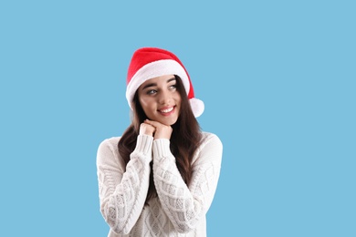 Photo of Beautiful woman wearing Santa Claus hat on light blue background