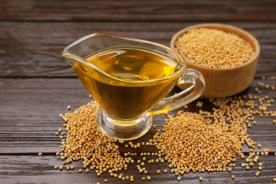Photo of Jug of natural oil and mustard seeds on wooden table
