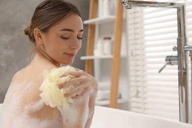 Woman taking bath with shower gel in bathroom, space for text