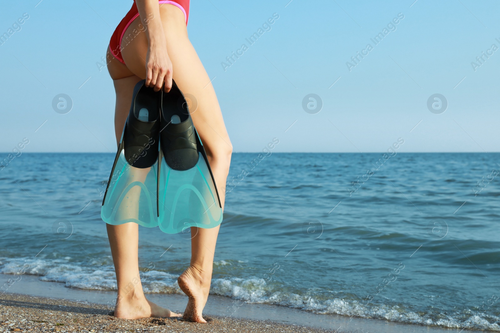 Photo of Woman with flippers near sea on beach, closeup