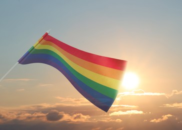 Image of Bright rainbow LGBT flag against sky at sunrise