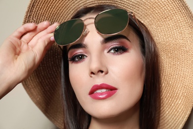 Photo of Beautiful woman with stylish sunglasses and hat on beige background