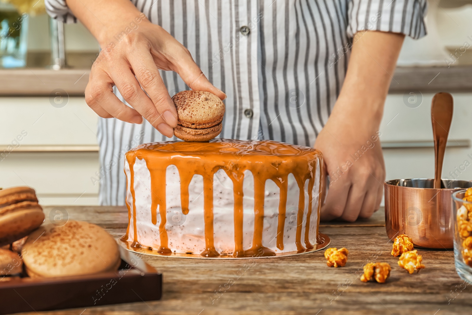 Photo of Young woman decorating delicious caramel cake at table