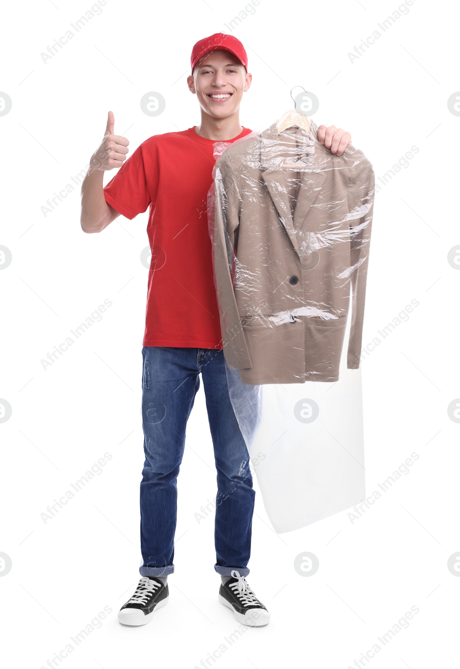 Photo of Dry-cleaning delivery. Happy courier holding jacket in plastic bag and showing thumbs up on white background