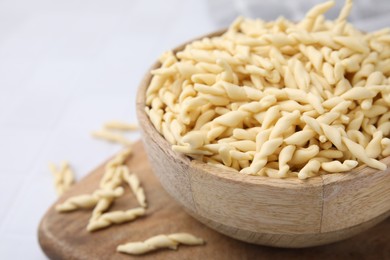 Photo of Bowl with uncooked Italian trofie pasta on white table, closeup. Space for text