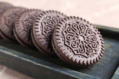 Tasty chocolate cookies with cream in wooden box, closeup