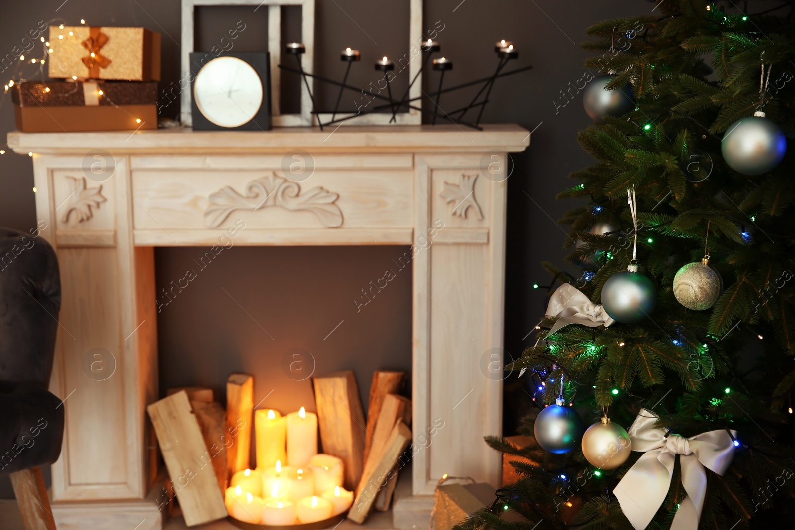 Photo of Decorative fireplace with wood near Christmas tree indoors. Stylish room interior