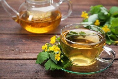 Photo of Aromatic celandine tea and flowers on wooden table, closeup. Space for text