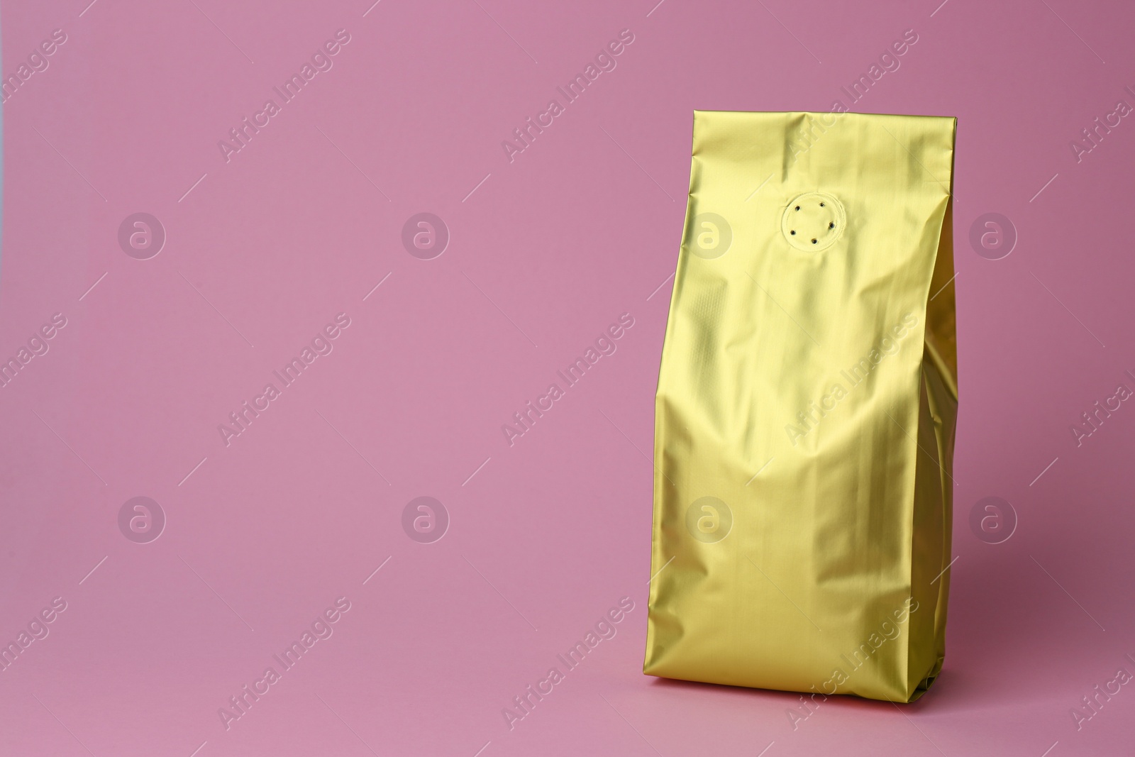 Photo of One blank foil package on pink background. Space for text