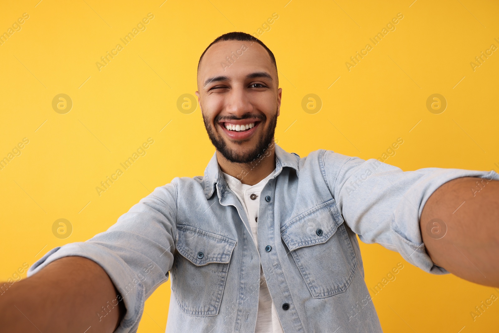 Photo of Smiling young man taking selfie on yellow background