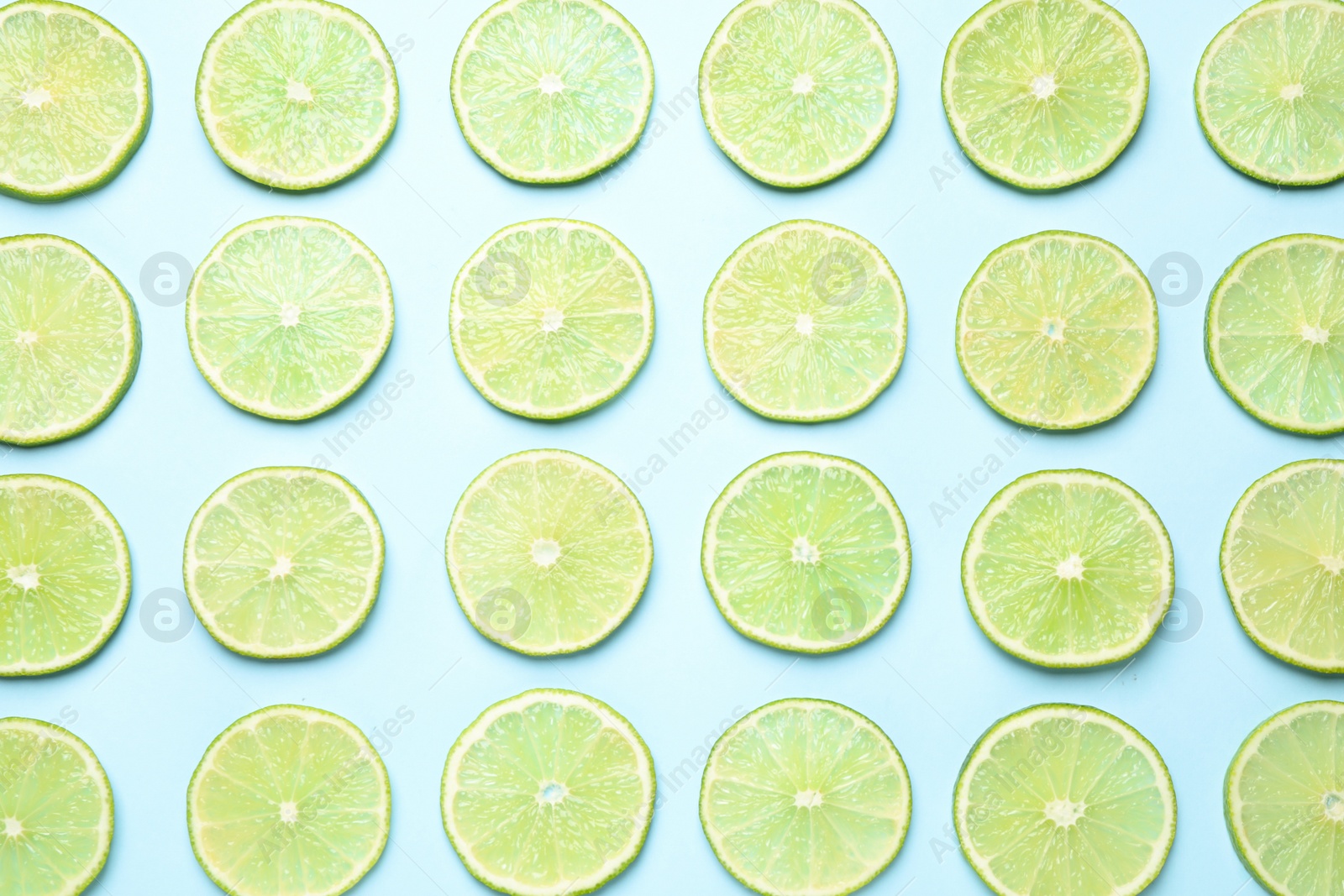 Photo of Fresh juicy lime slices on light blue background, flat lay