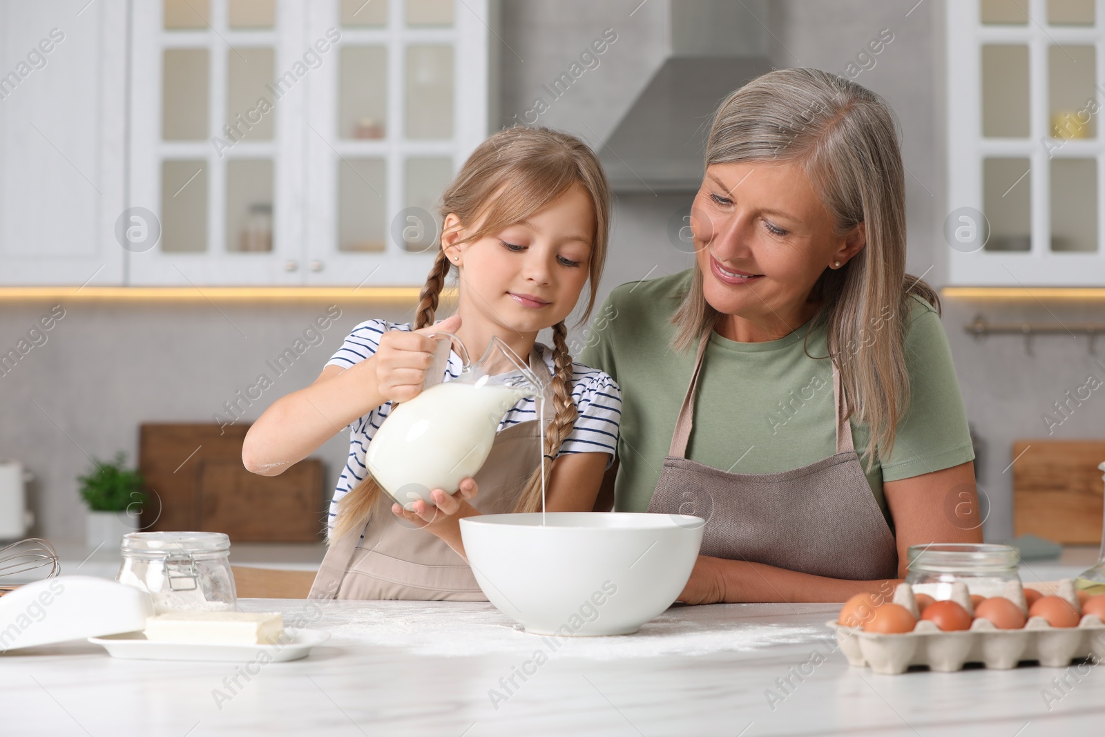 Photo of Happy grandmother with her granddaughter cooking together in kitchen