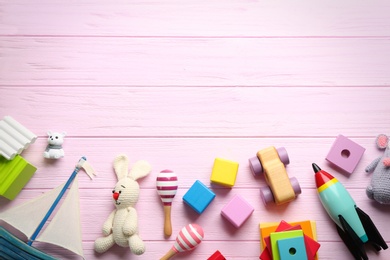 Different toys on pink wooden background, flat lay. Space for text