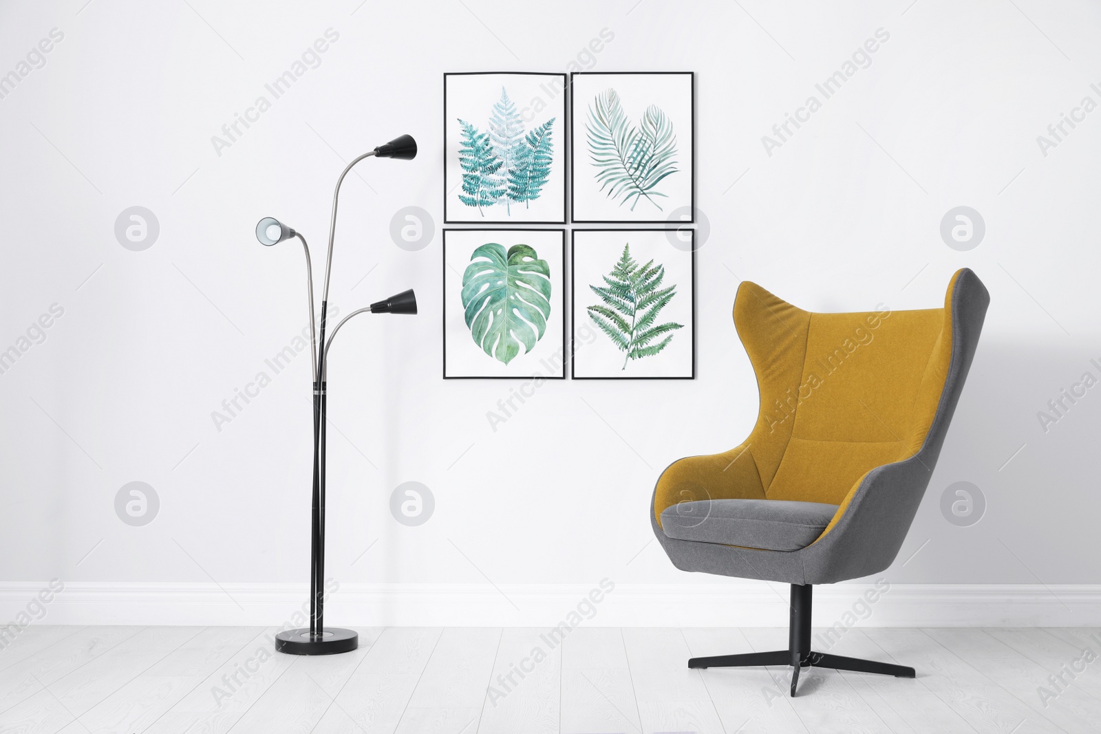 Photo of Stylish room interior with comfortable armchair and paintings of tropical leaves