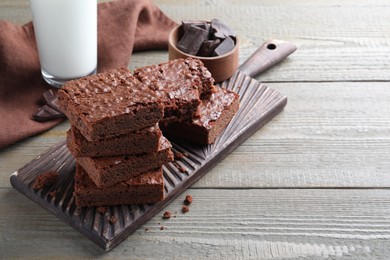Photo of Delicious chocolate brownies on wooden table. Space for text